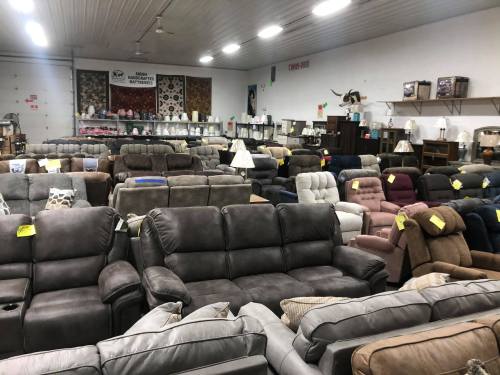 A spacious furniture store filled with various couches and recliners, some with lamps and decorative items in the background.