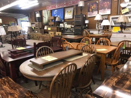 A furniture store display featuring various tables, chairs, and lamps in a well-lit interior.