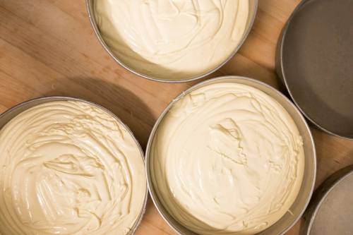 Two round cake pans filled with smooth, creamy batter on a wooden surface.
