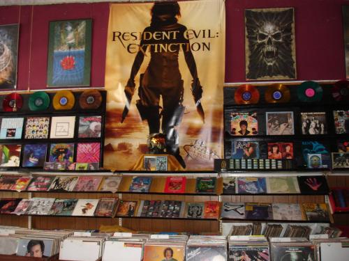 A wall filled with vinyl records and posters, including a large "Resident Evil: Extinction" banner.