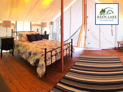 Cozy glamping tent interior with a bed, nightstands, and a rug, featuring warm lighting and a welcoming atmosphere.