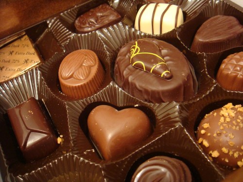 A variety of assorted chocolates in a box, featuring different shapes and designs, including hearts and swirls.