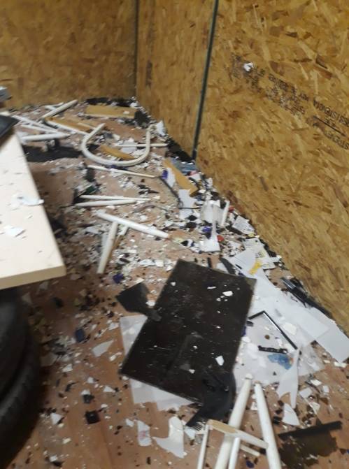 A cluttered room with debris, including broken materials and scattered pieces, on the floor and against the walls.
