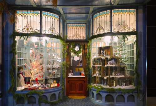 A charming shop window decorated for the holidays, featuring festive displays and greenery.