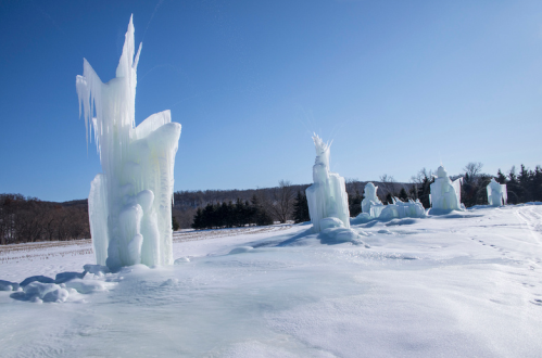 Ice formations rise majestically from a snowy landscape under a clear blue sky, creating a winter wonderland scene.