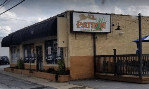 Exterior of El Patron Mexican Restaurant, featuring a sign, outdoor seating, and a brick facade.