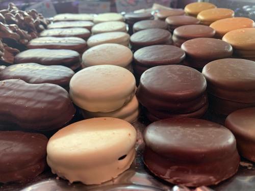 A variety of chocolate-covered cookies arranged in rows, featuring different flavors and colors.