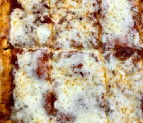 A close-up of a rectangular pizza topped with melted cheese and tomato sauce, cut into squares.