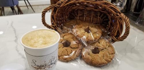 A basket of cookies with a chocolate kiss, next to a cup of coffee on a marble countertop.