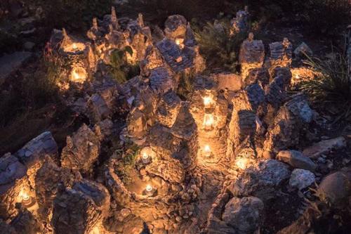 A miniature stone village illuminated by candles, creating a warm, enchanting atmosphere at night.