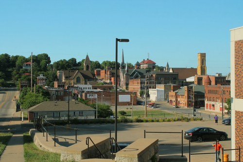A scenic view of a small town with historic buildings, churches, and a clear blue sky in the background.