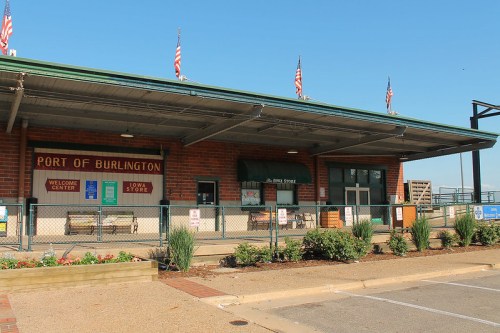 Exterior view of the Port of Burlington building with flags, signage, and landscaped area in front.