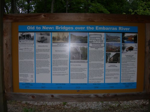 Informational sign detailing the history of bridges over the Embarras River, featuring images and timelines from 1830 to 2001.