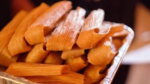 A tray filled with neatly arranged tamales, showcasing their corn husk wrappers.