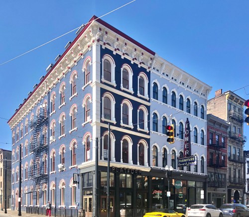 Historic building with blue and white facade, featuring arched windows and a ground-level furniture store. Clear blue sky.