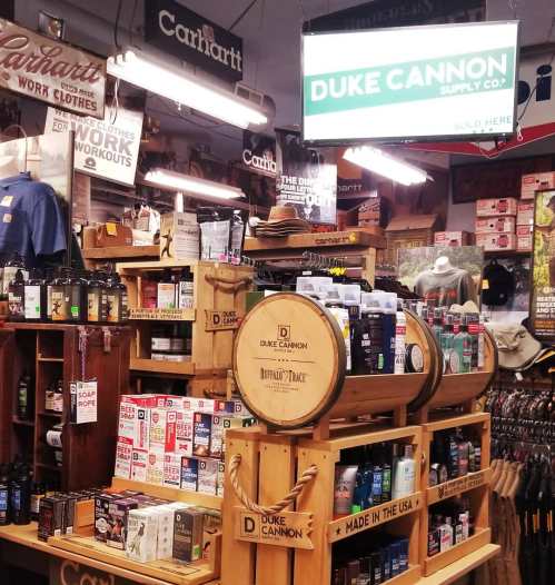 Display of Duke Cannon products in a retail store, featuring grooming items and branded merchandise on wooden shelves.