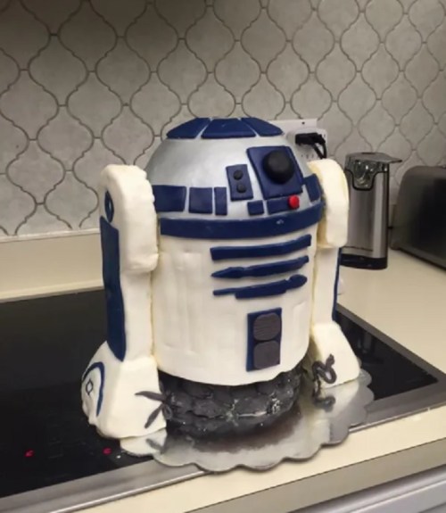 A cake shaped like R2-D2, featuring blue and white icing, placed on a kitchen countertop.