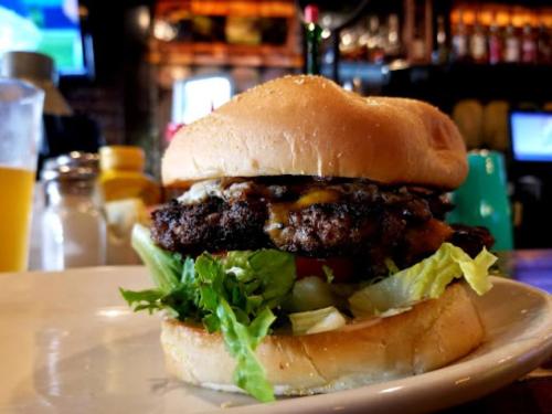 A close-up of a juicy burger with lettuce, tomato, and melted cheese, served on a soft bun.