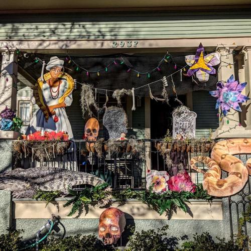A decorated porch featuring Halloween-themed decorations, including skeletons, tombstones, and colorful lights.