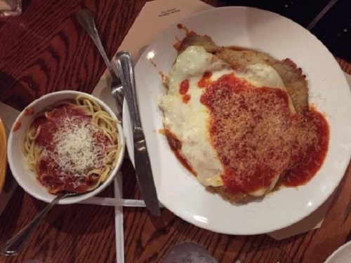 A plate of chicken parmesan topped with marinara sauce and melted cheese, alongside a bowl of spaghetti with sauce and cheese.