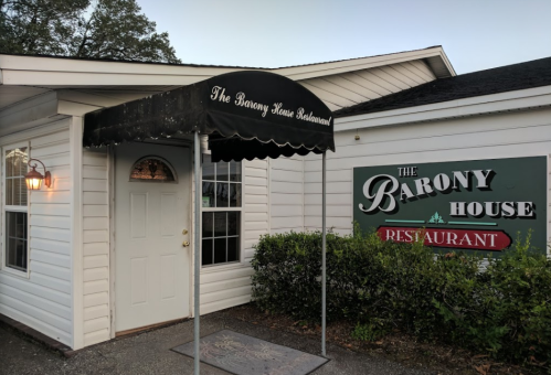 Exterior of The Barony House Restaurant, featuring a covered entrance and a sign with the restaurant's name.