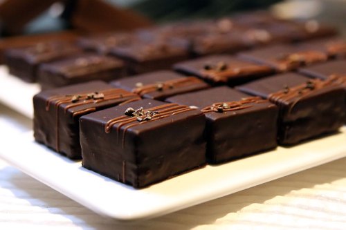 A platter of rectangular chocolate-covered treats, drizzled with chocolate and garnished with small decorations.