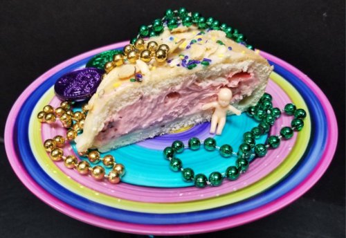 A colorful plate holds a slice of cake topped with beads, sprinkles, and a small figurine.