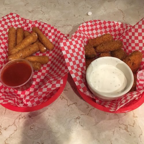 Two baskets of fried snacks: one with mozzarella sticks and marinara sauce, the other with crispy chicken bites and ranch dressing.