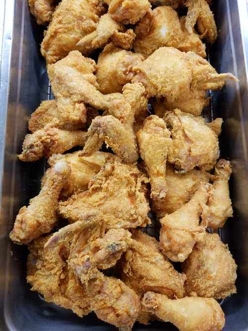 A tray filled with golden-brown, crispy fried chicken pieces.