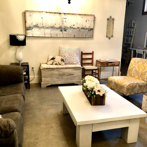 Cozy living room with a gray sofa, patterned chairs, a white coffee table, and decorative wall art.