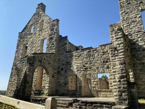 Ruins of a stone building under a clear blue sky, with several windows and an open doorway visible.