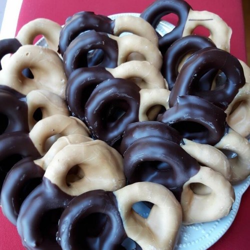 A plate of assorted pretzels, some coated in chocolate and others in a light caramel color.