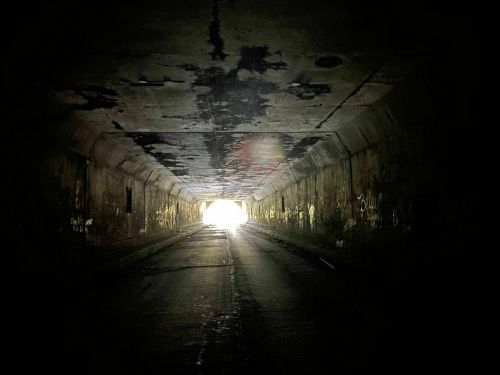A dark tunnel with a bright light at the end, illuminating the path ahead.