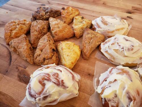A variety of baked goods including scones and cinnamon rolls arranged on a wooden surface.