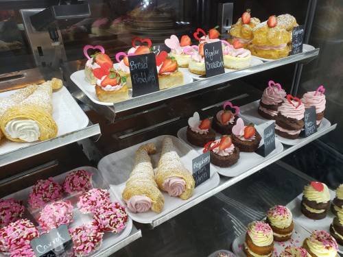 A display of assorted pastries and desserts, including cupcakes, cream puffs, and heart-shaped decorations.