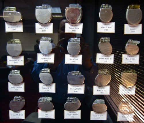 A display case featuring various models of pacemakers from different years, labeled with their names and release dates.
