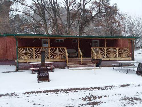 A cozy cabin with a wooden porch, surrounded by snow and trees, on a winter day.