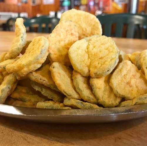 A silver platter piled high with crispy, golden fried pickles.