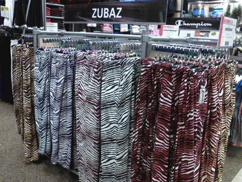 A display of colorful Zubaz pants in various zebra patterns hanging on racks in a store.