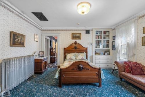 Cozy bedroom with vintage decor, featuring a wooden bed, patterned carpet, and a radiator.