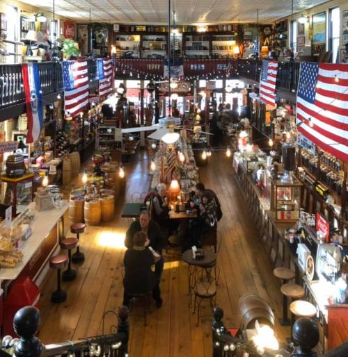 A cozy, vintage-style café with American flags, wooden floors, and patrons enjoying their time at tables.