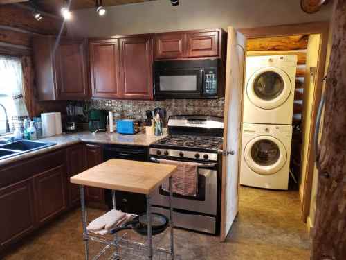 Cozy kitchen with wooden cabinets, stainless steel appliances, and a laundry area visible through an open door.