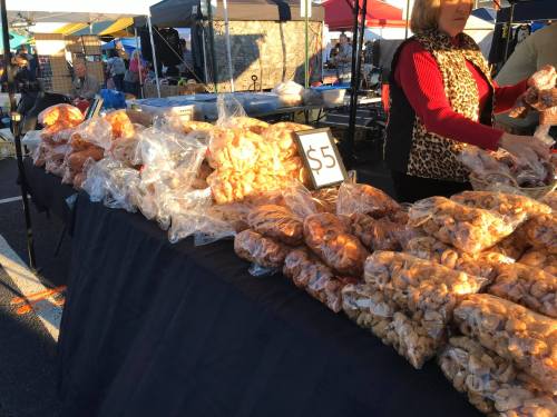 A market stall displaying bags of snacks, with a sign reading "$5" and a vendor in the background.