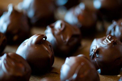Close-up of glossy chocolate truffles arranged on a surface, showcasing their rich, dark coating.