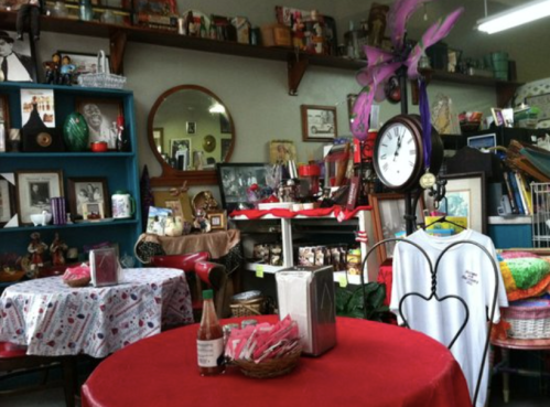A cozy vintage shop with colorful decor, tables, and various antiques displayed on shelves and walls.