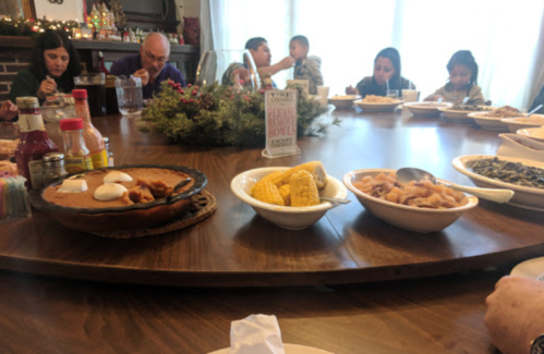 A festive table filled with various dishes, surrounded by people enjoying a meal together in a cozy setting.