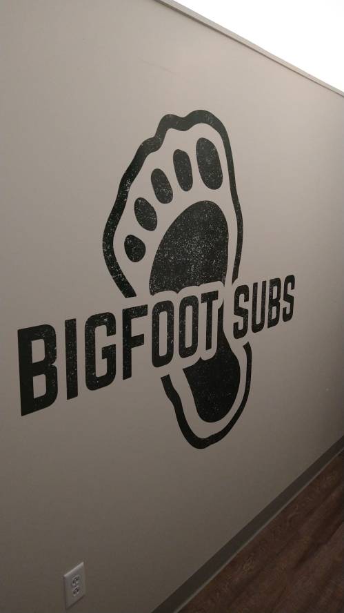 A wall mural featuring a large footprint and the text "BIGFOOT SUBS" in bold letters.