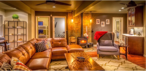 Cozy living room with a brown leather sofa, a wooden coffee table, and a small stove, featuring warm lighting and decor.