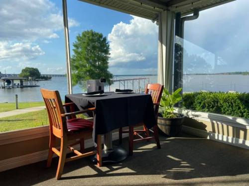 A cozy restaurant table by a large window, overlooking a scenic view of water and trees.