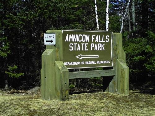 Sign for Amnicon Falls State Park, with arrows pointing left to U.S. Hwy 2 and right for park entrance.